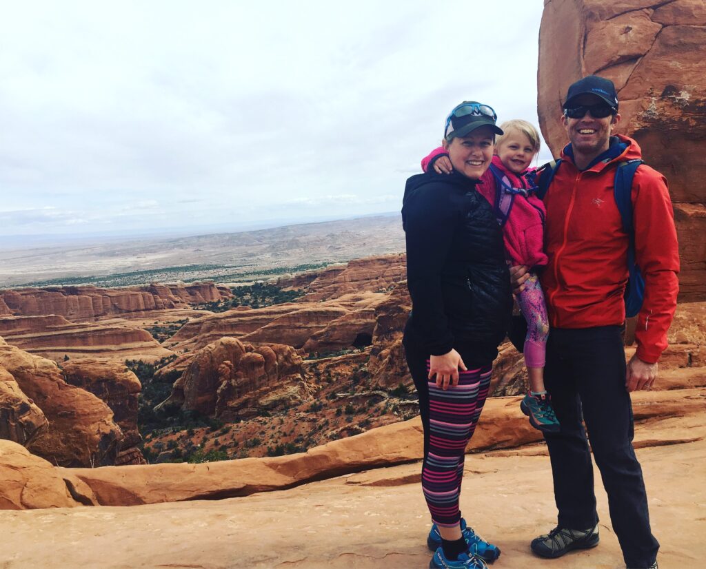 A happy family holding their daughter at Arches National Park
