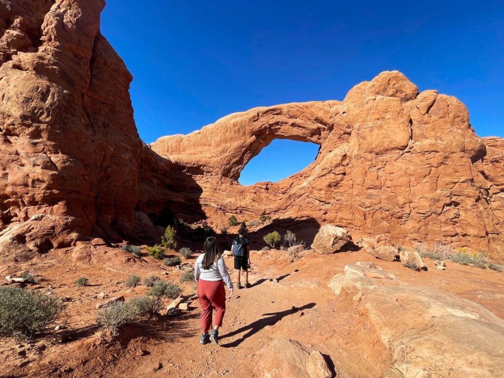 Two hikers in front of Window Arch in Arches National Park